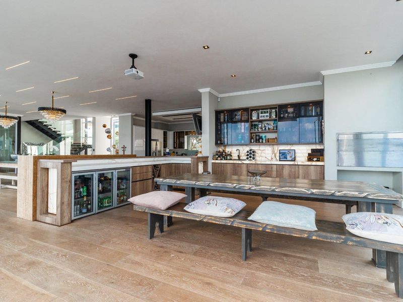 Spacious open-plan living area featuring a high-end built-in bar with stone countertops, integrated undercounter fridges, custom cabinetry, and premium timber flooring.