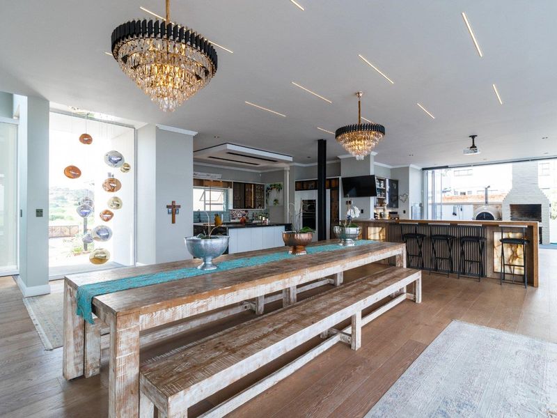 Spacious open-plan living and dining area featuring high-end finishes, crystal chandeliers, modern kitchen cabinetry, and seamless flow to an outdoor entertainment space.