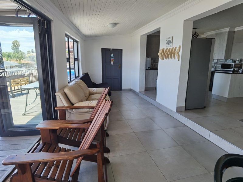 A spacious enclosed patio featuring tiled flooring, beadboard ceiling, and bi-fold glass doors that open onto an outdoor deck area.