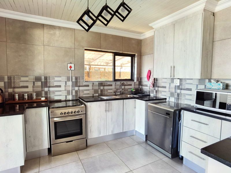 Modern kitchen featuring light wood-grain cabinetry, granite countertops, stainless steel appliances, tiled backsplash, and a distinctive tongue and groove ceiling.