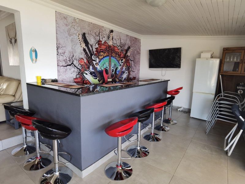 A dedicated bar area featuring a built-in counter with a granite top, tiled flooring, and a tongue and groove ceiling.