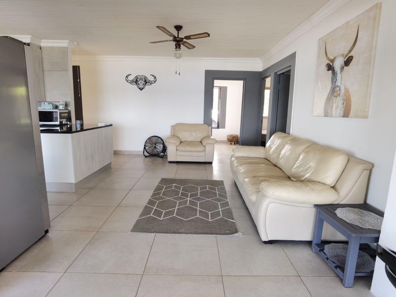 Open plan living area featuring tiled flooring, a kitchen island with granite countertops, and a ceiling fan, creating a functional and connected living space.
