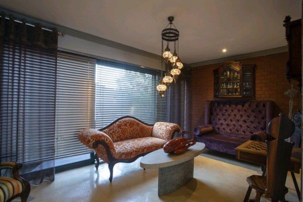 A living room featuring an exposed brick feature wall, polished concrete flooring, and large sliding glass doors with venetian blinds.
