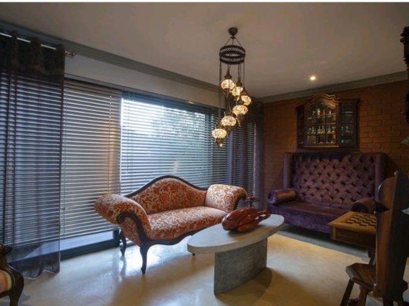 A living room featuring an exposed brick feature wall, polished concrete flooring, and large sliding glass doors with venetian blinds.