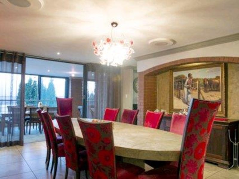 Spacious dining room featuring large format floor tiles, a decorative brick archway, and direct access to an outdoor patio area through sliding glass doors.