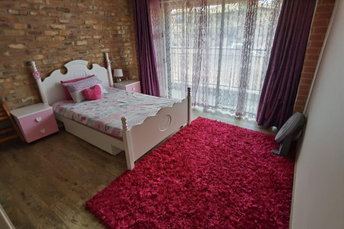 Bedroom featuring a rustic exposed brick feature wall and large sliding glass doors providing access to a balcony.