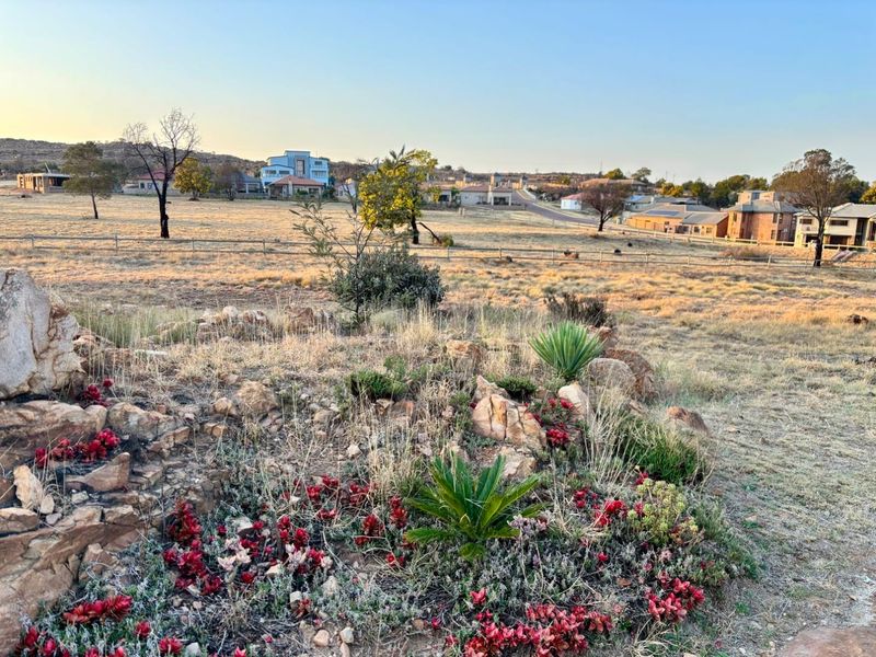 A scenic view of the vacant residential land featuring natural rock formations, established rockery landscaping, and surrounding neighbourhood vistas.