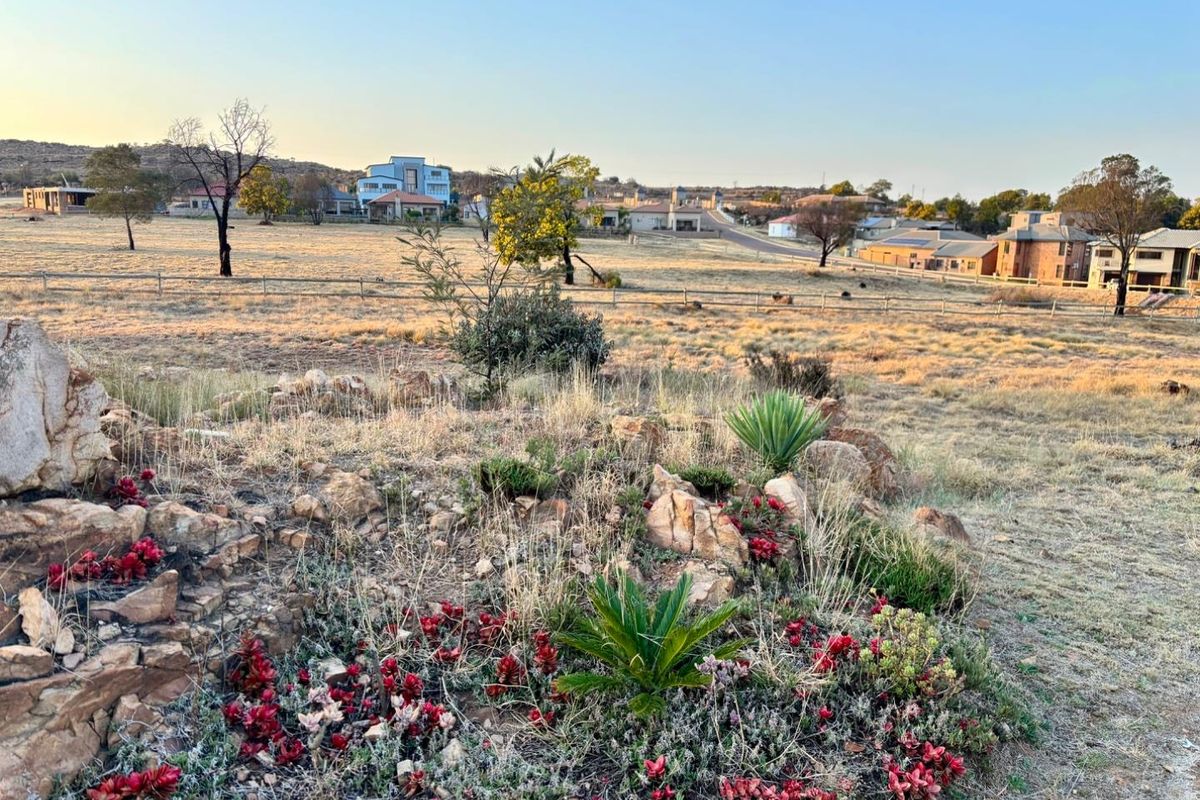 A scenic view of the vacant residential land featuring natural rock formations, established rockery landscaping, and surrounding neighbourhood vistas.