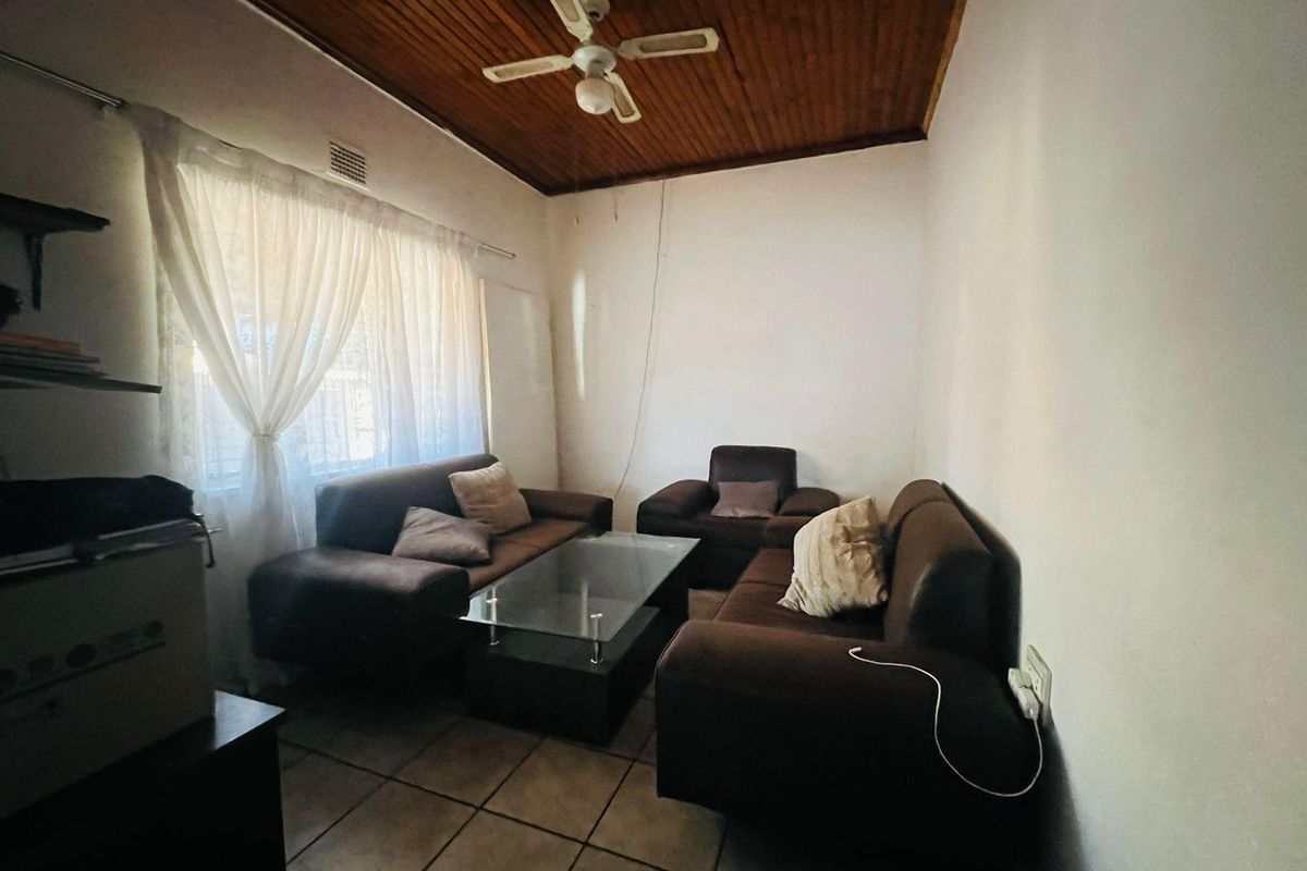 A living room featuring tiled flooring and a timber-clad ceiling with a mounted ceiling fan.