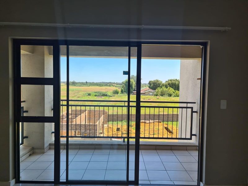 A covered balcony featuring tiled flooring and a metal balustrade, offering an open view of the surrounding landscape.