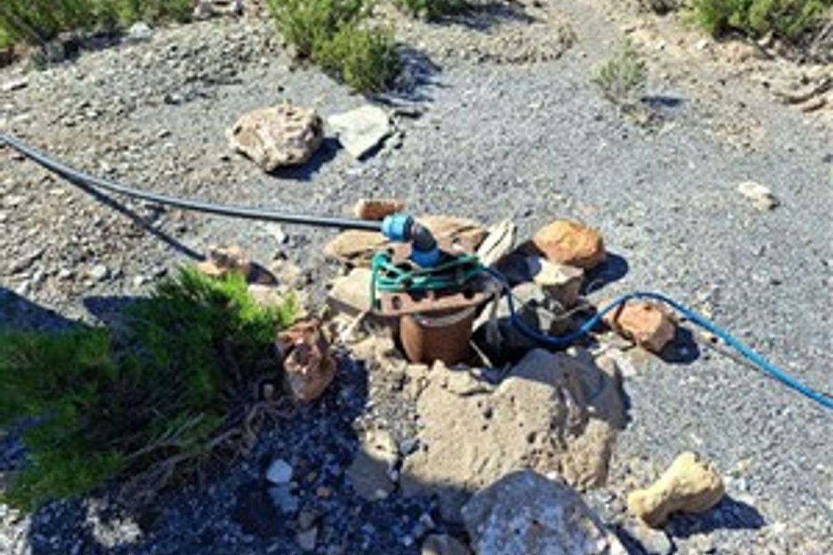 Outdoor borehole installation featuring a water pump and irrigation piping system located on the farm grounds.
