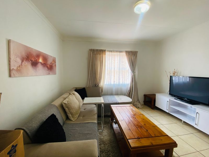 A functional living room featuring tiled flooring and neutral wall finishes, providing a comfortable and well-lit space for relaxation.