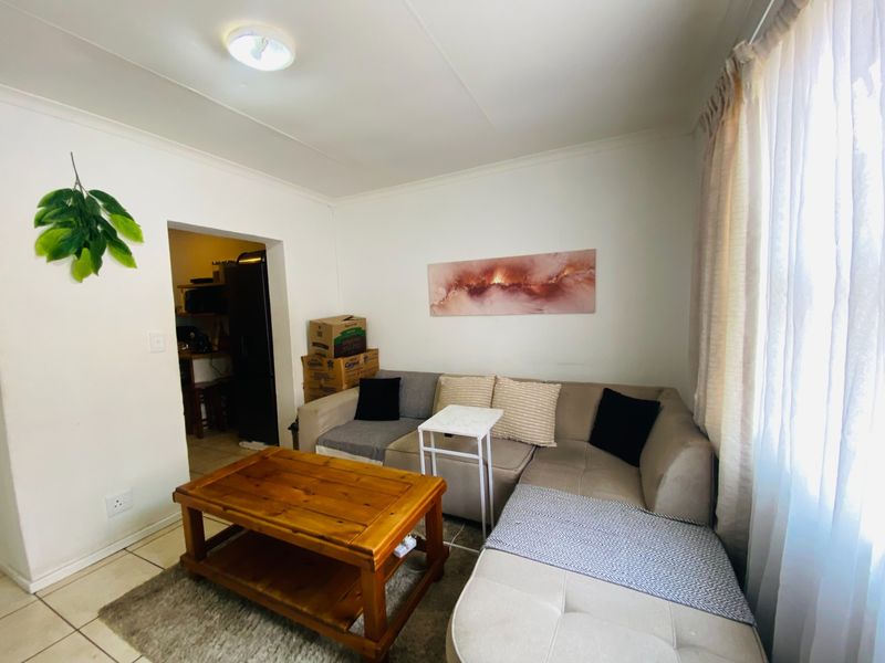 A functional living room area featuring tiled flooring and neutral wall finishes, providing a comfortable space with direct access to the kitchen area.