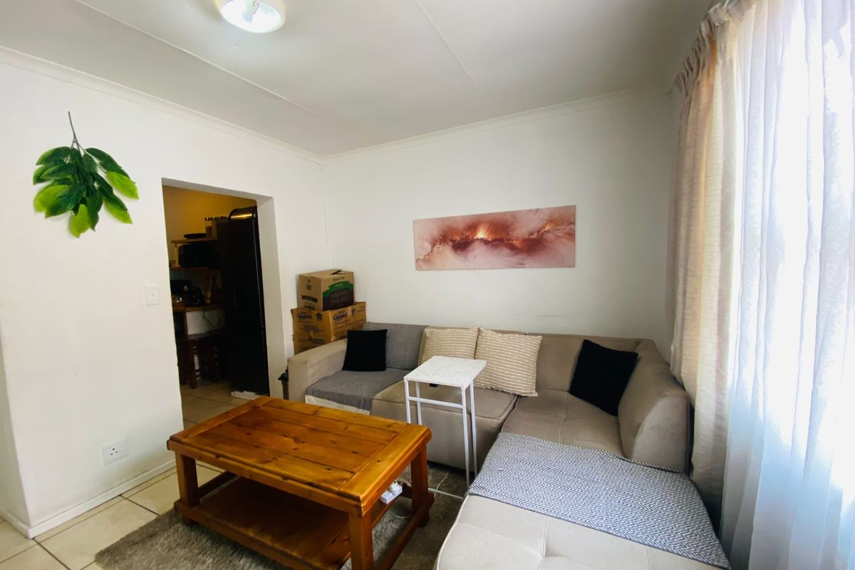 A functional living room area featuring tiled flooring and neutral wall finishes, providing a comfortable space with direct access to the kitchen area.
