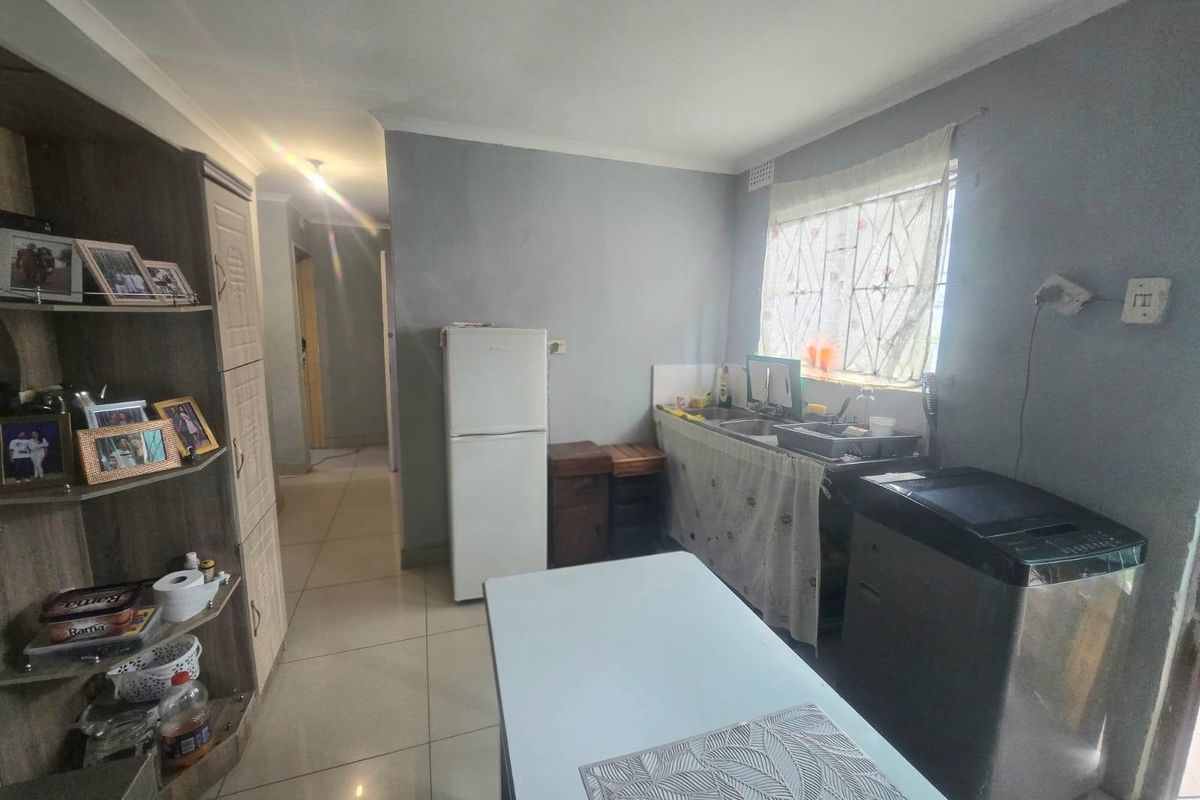 A functional kitchen area featuring tiled flooring, a double sink, and built-in cabinetry, providing a practical space for daily meal preparation and utility tasks.