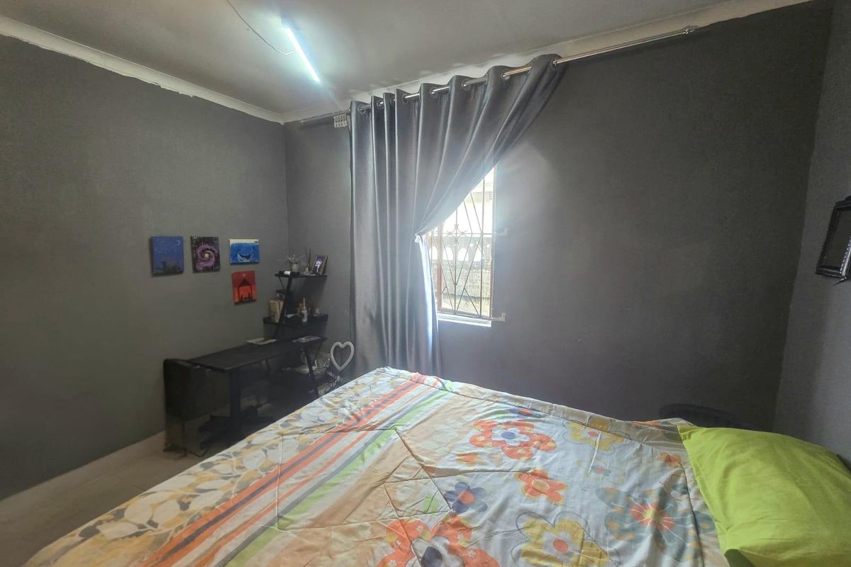 A bedroom featuring dark grey walls, a window with security bars, and a curtain rod.