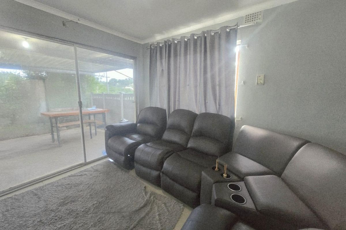 A living room featuring large sliding glass doors that provide access to an outdoor patio area, with neutral wall finishes and tiled flooring.