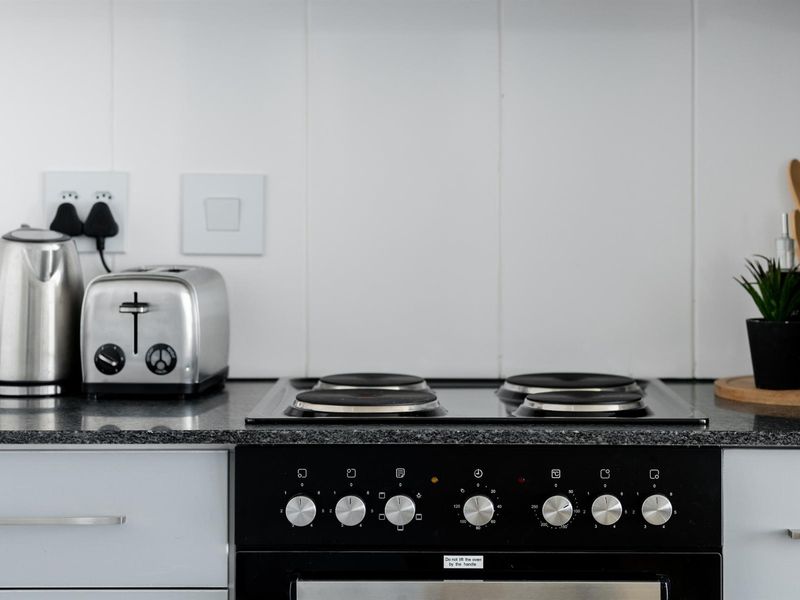 A clean kitchen workspace featuring a built-in electric oven, hob, and durable granite countertops with a tiled splashback.