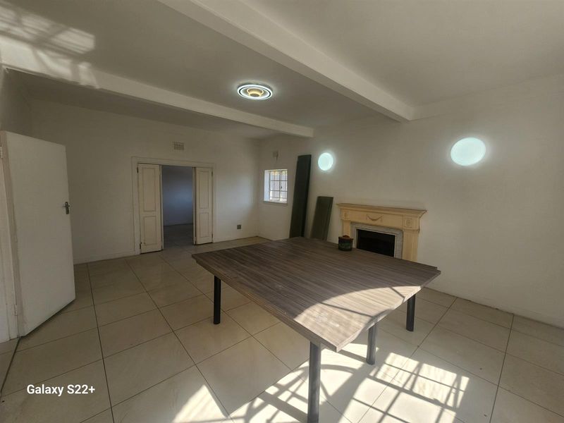 Spacious living room featuring tiled flooring, a traditional fireplace, and double door access to adjacent rooms.