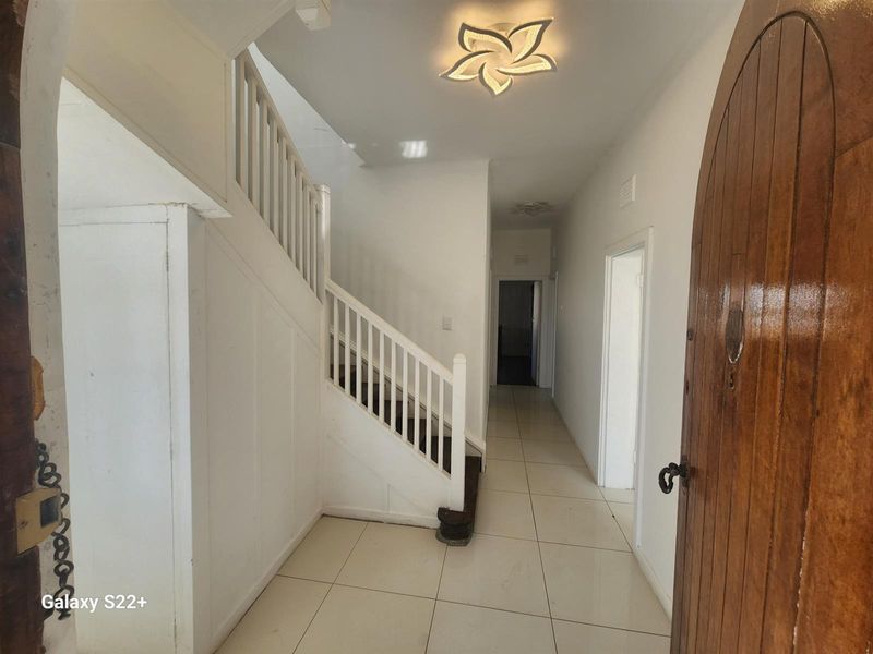 Entrance hallway featuring tiled flooring, a wooden front door, and a staircase with white balustrades leading to the upper level.