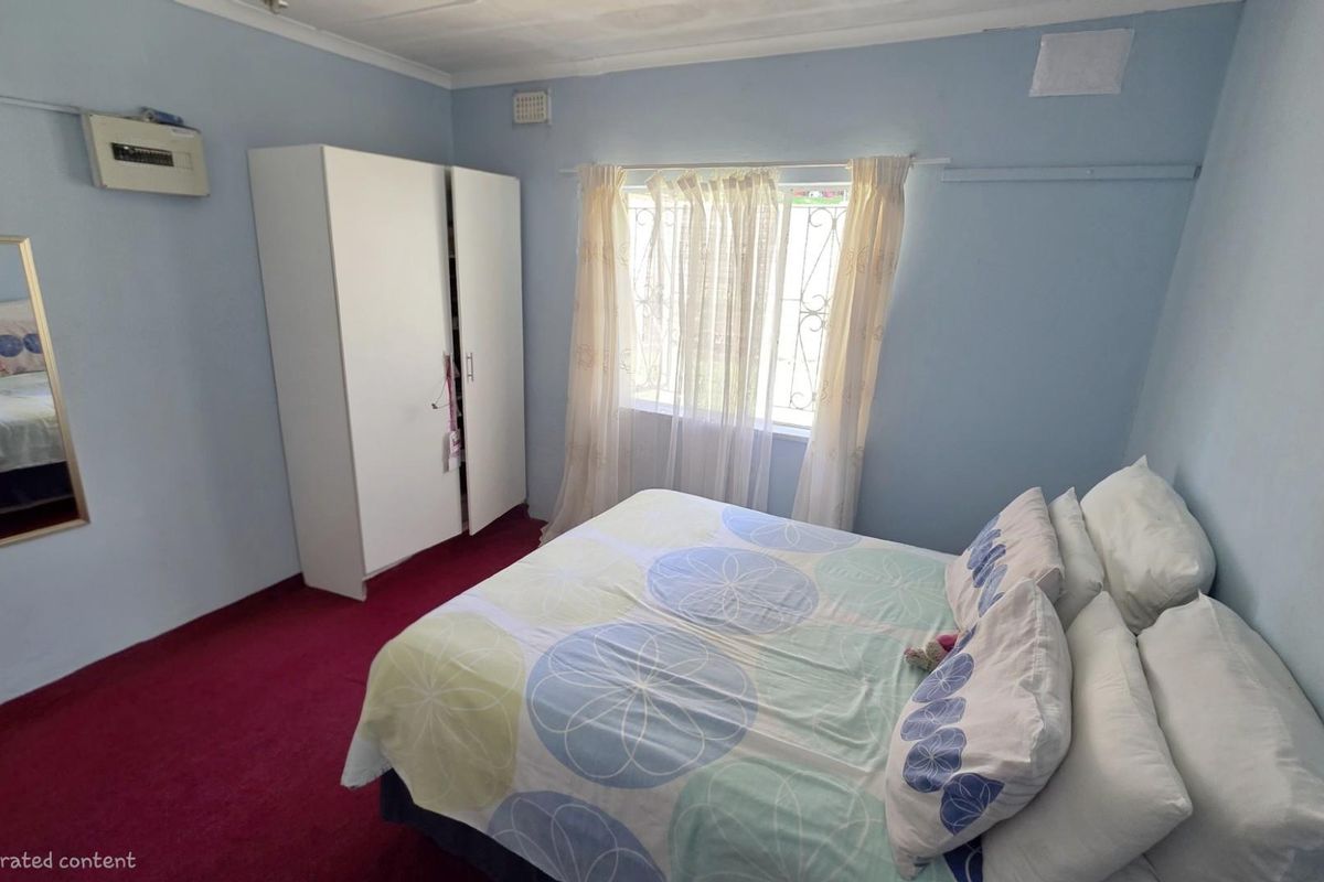 A bedroom featuring red carpeting, light blue walls, and a window with security bars.