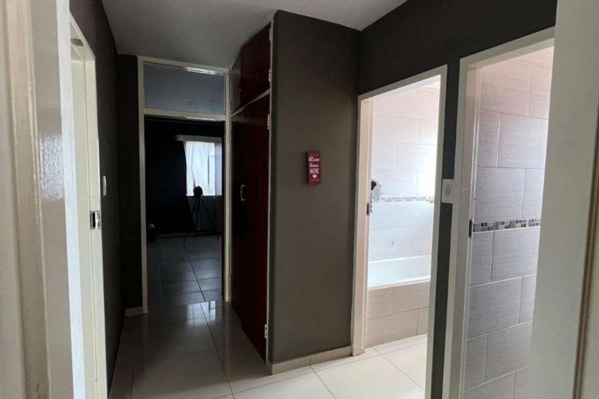 A functional hallway featuring tiled flooring, built-in storage cabinetry, and access to adjacent rooms including a bathroom.