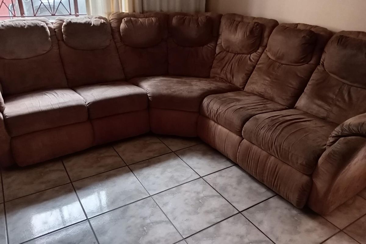 A living room area featuring tiled flooring and a large corner sofa arrangement.