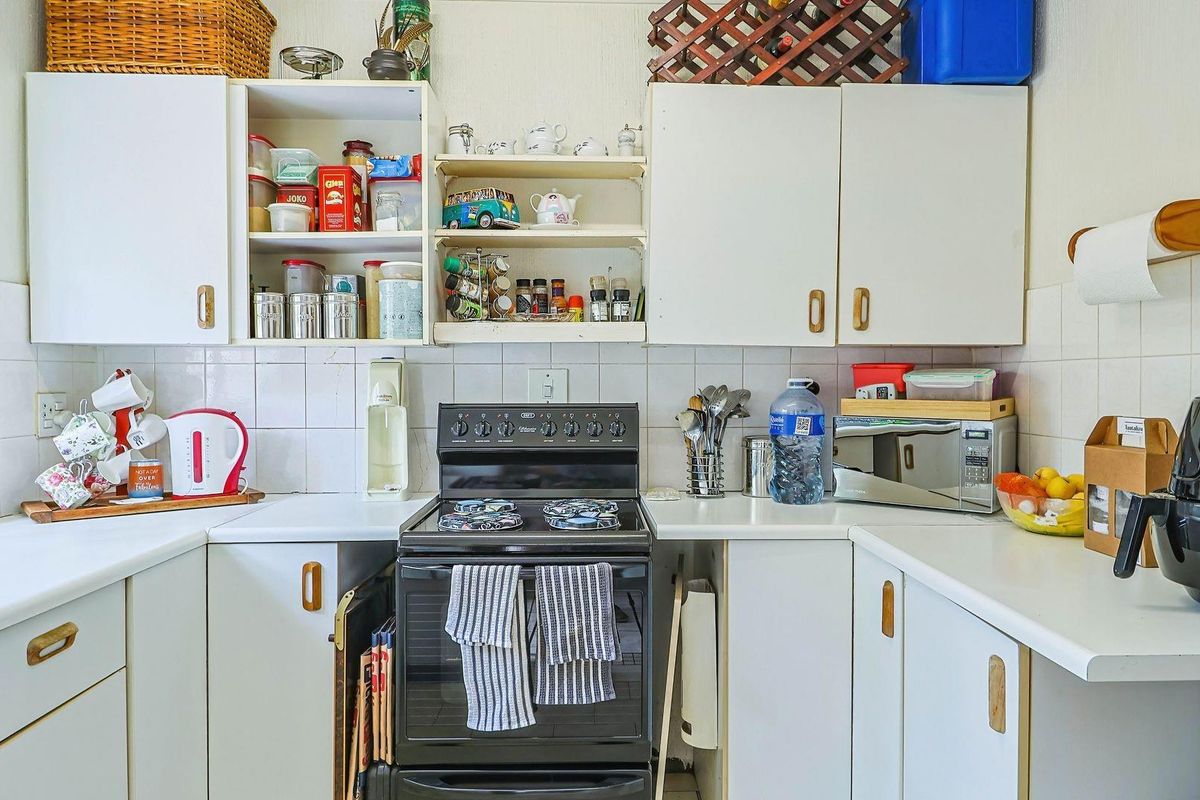 A functional kitchen featuring white cabinetry, tiled backsplash, and a freestanding stove, offering a practical layout with ample storage space.
