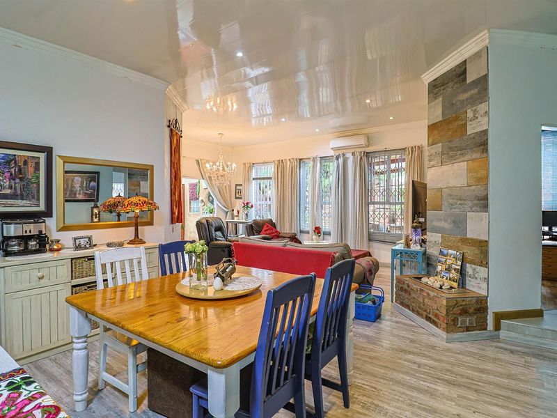 Spacious open-plan living and dining area featuring a prominent stone-clad fireplace, glossy ceiling finish, and split-system air conditioning.