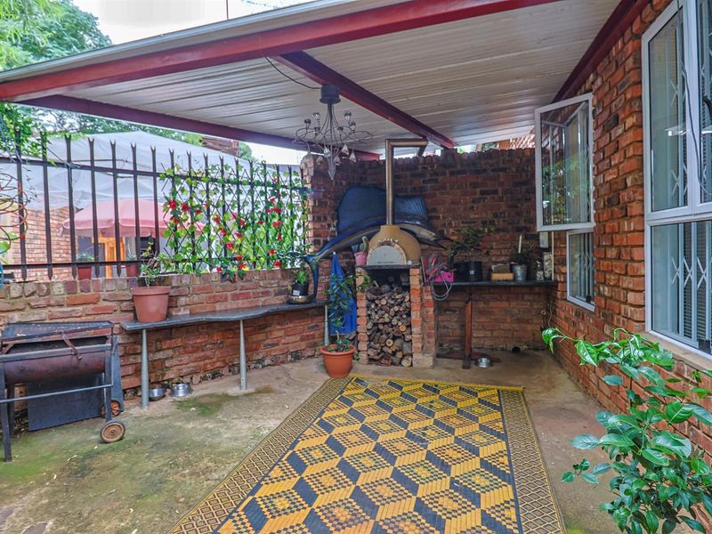Covered outdoor patio area featuring a built-in pizza oven, brick wall construction, and direct access to the home.