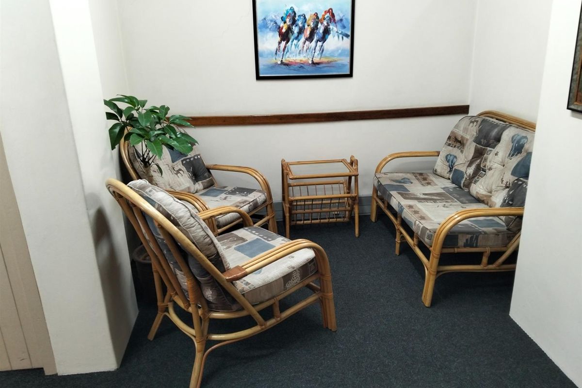 A small, carpeted waiting area or breakout space featuring a dado rail and neutral wall finishes.