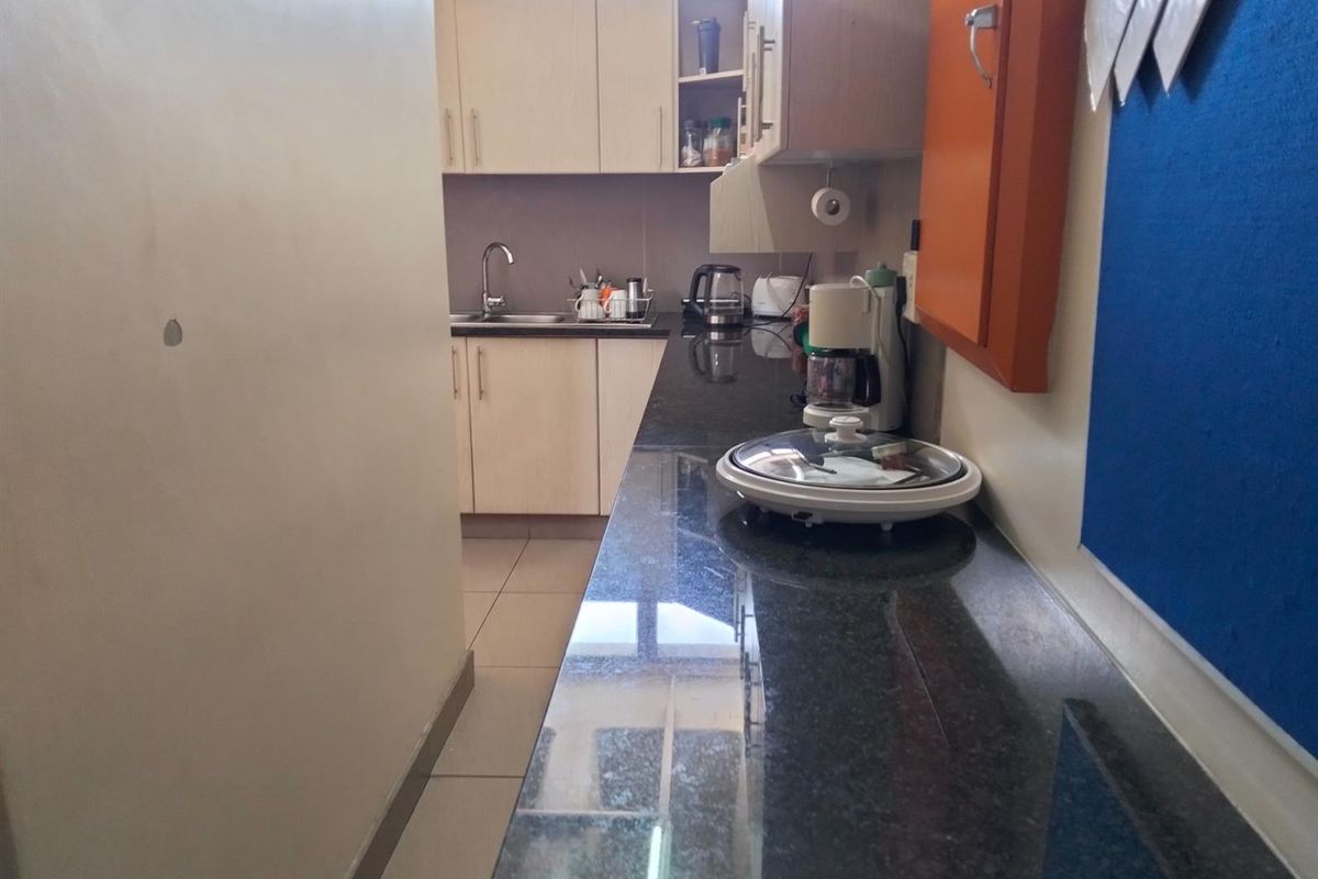 A functional kitchenette featuring dark granite countertops, light wood cabinetry, and a stainless steel sink.