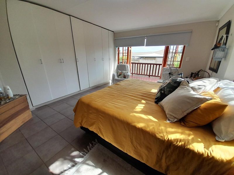 Spacious bedroom featuring extensive built-in cupboards, tiled flooring, and direct access to a private balcony through wooden doors.