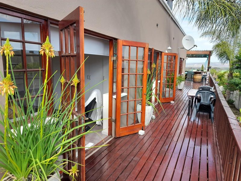 A spacious timber deck balcony featuring multiple sets of wooden french doors providing access to the interior living space.