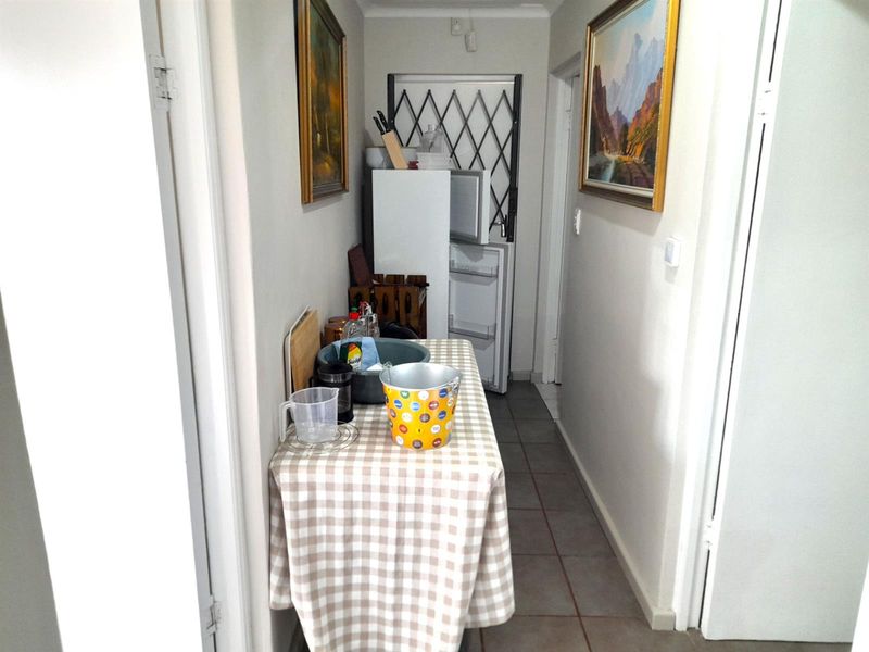 A narrow hallway featuring tiled flooring and a security gate at the end, providing access to adjacent rooms.