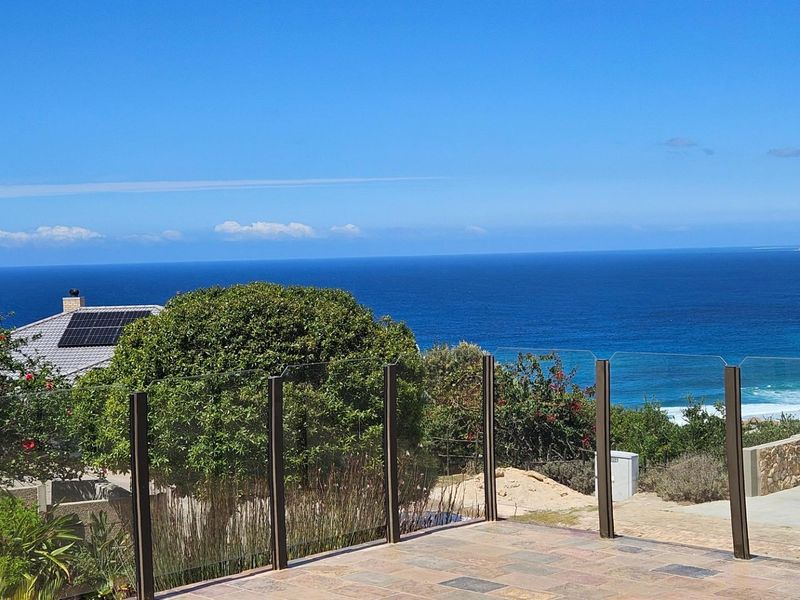 Elevated outdoor patio featuring a modern glass balustrade with expansive, unobstructed ocean views.