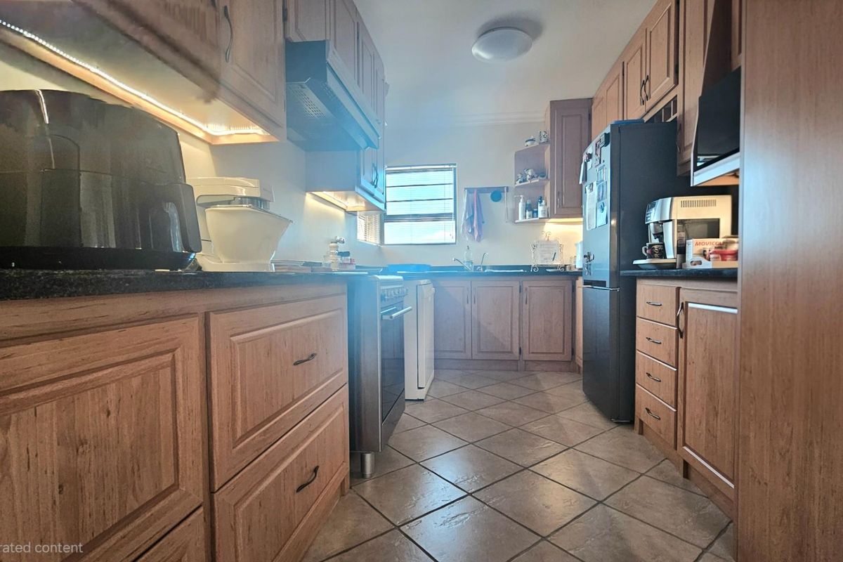 A functional kitchen featuring wooden cabinetry, laminate countertops, tiled flooring, and integrated appliances, offering a classic and practical layout.