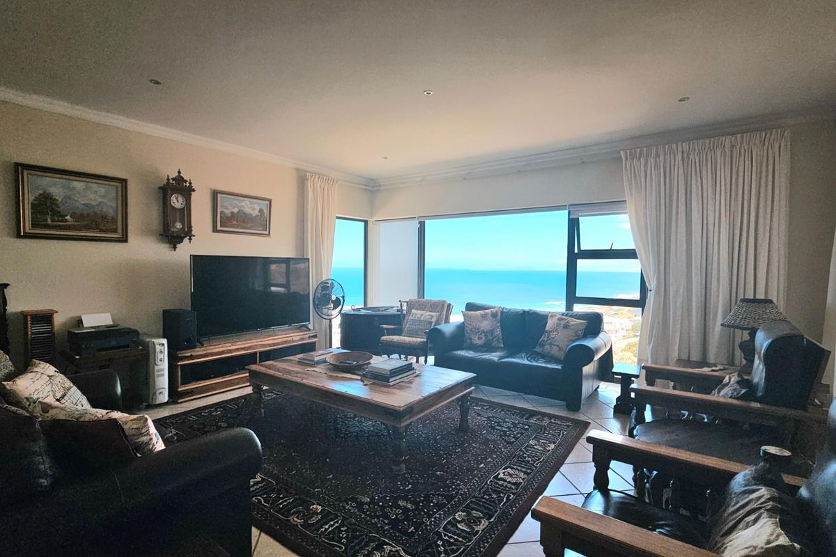 Spacious living room featuring large windows with expansive ocean views, tiled flooring, and recessed lighting.