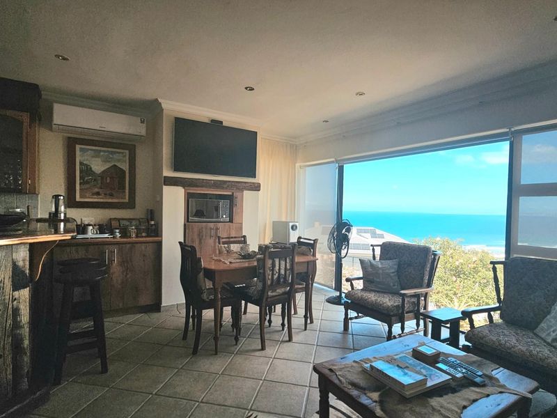 Open-plan living and dining area featuring tiled floors, built-in cabinetry, and large sliding doors offering expansive ocean views.
