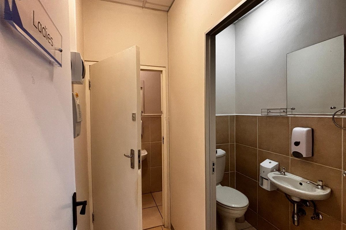 A functional ladies' restroom facility featuring tiled walls, a wall-mounted basin, and a standard toilet, maintained in a clean and practical condition.