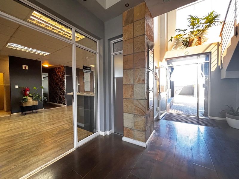 Modern office entrance lobby featuring a stone-clad pillar, glass partitions, and a bright, welcoming reception area with high-quality flooring finishes.