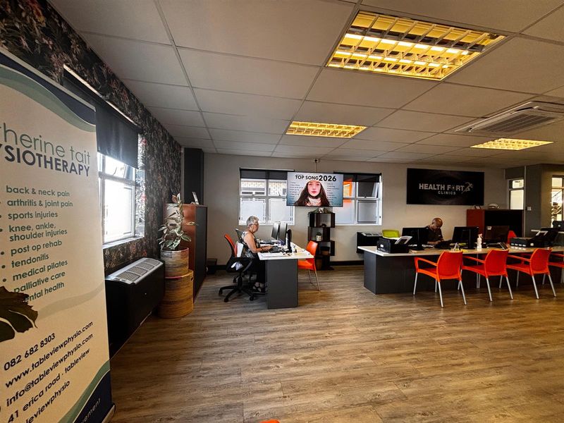 A functional office space featuring laminate flooring, suspended ceilings with recessed lighting, and integrated air conditioning, currently utilized as a physiotherapy clinic.