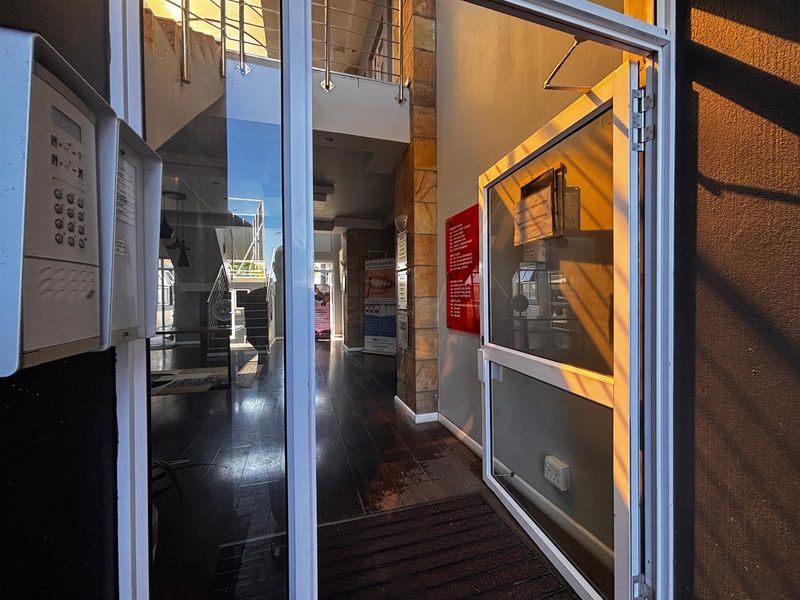 Entrance lobby of an office building featuring stone cladding, a staircase with stainless steel balustrades, and an intercom system.