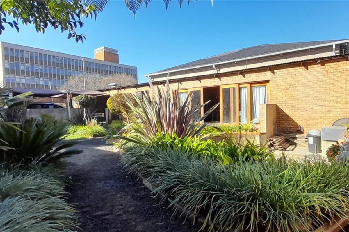Rear view of a face brick house featuring timber-framed sliding doors opening onto a landscaped garden area.