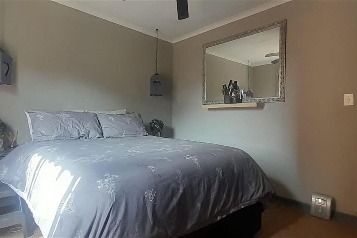 A standard bedroom featuring neutral wall tones, coving, and a ceiling fan, providing a functional and comfortable sleeping space.
