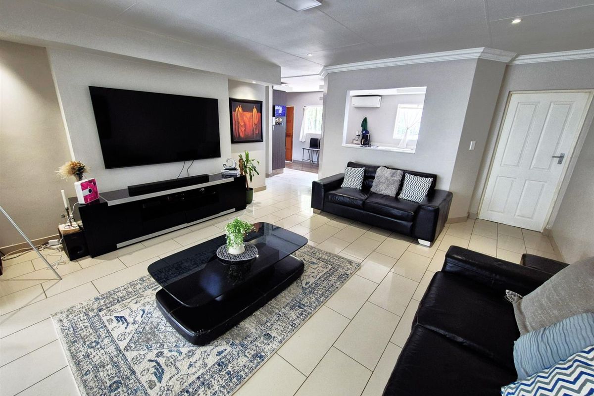 Spacious living room featuring tiled flooring, recessed wall niche for media, and a pass-through window connecting to the adjacent kitchen area.