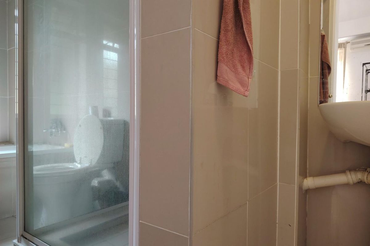 A bathroom featuring a glass-enclosed shower, a toilet, and a wall-mounted sink with visible plumbing.