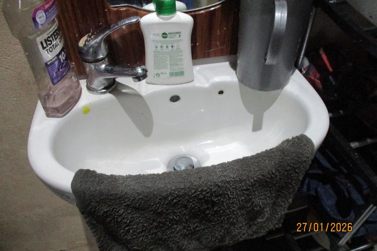 A close-up view of a bathroom basin featuring a chrome mixer tap and wall-mounted mirror.