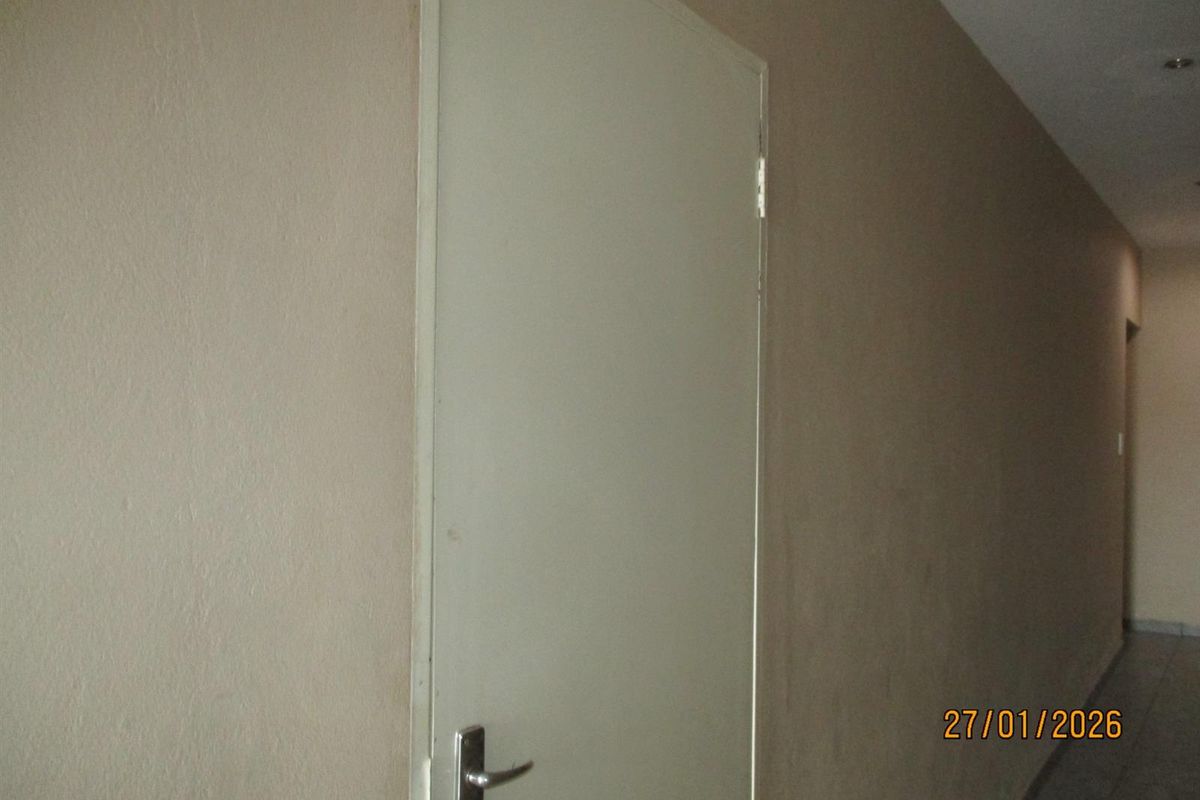 A simple interior hallway featuring plain walls and recessed ceiling lighting.