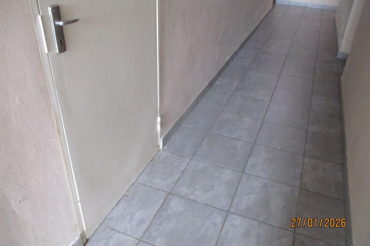 A simple, tiled hallway providing access to adjacent rooms, featuring neutral wall finishes and standard internal doors.